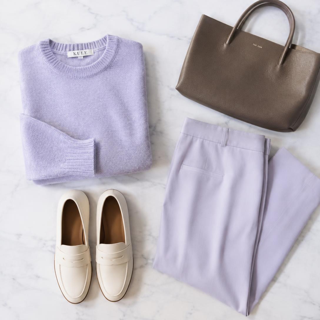 A curated outfit laid flat with knitwear, trousers, loafers, and a leather tote